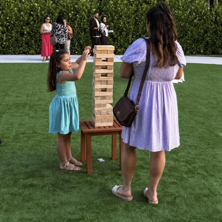 Giant Jenga – Stacking Game rental at a Miami wedding event with a child playing the wooden stacking game outdoors.